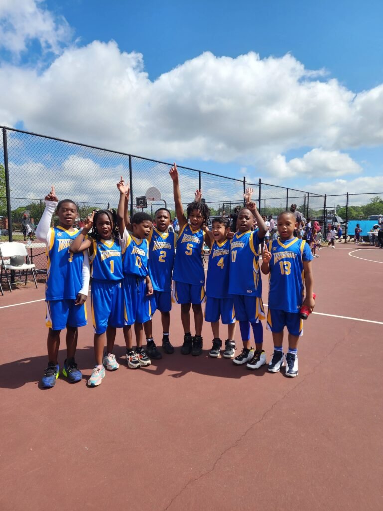 Just Kingdom Sports youth basketball team celebrating on an outdoor court in Henry County